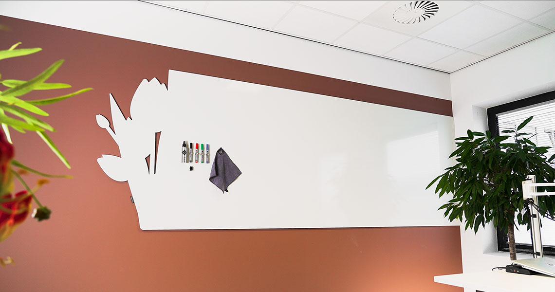 Bespoke whiteboard wall with a floral silhouette cut into a rust-toned wall