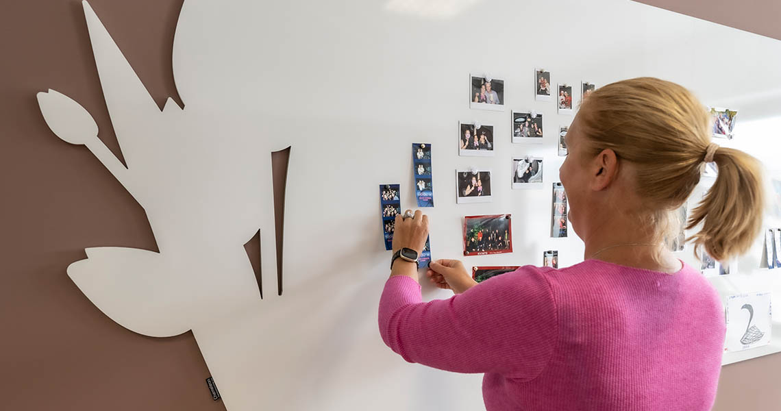 Colleague pinning photos to a floral-cutout bespoke whiteboard wall