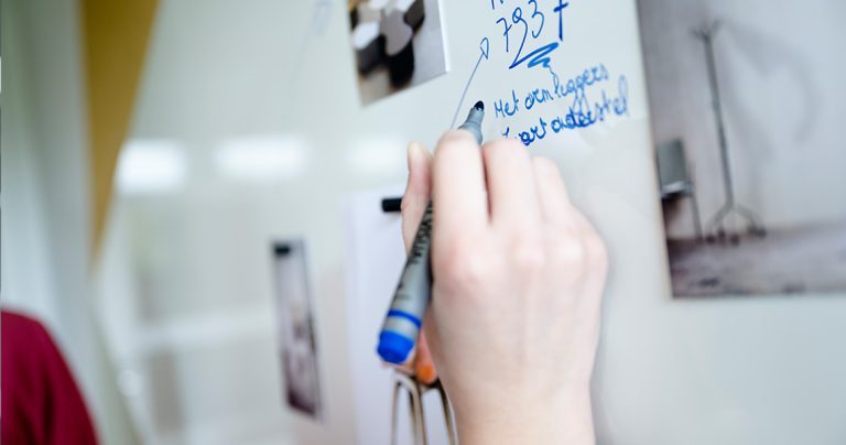 Close-up of a hand writing on a custom magnetic whiteboard