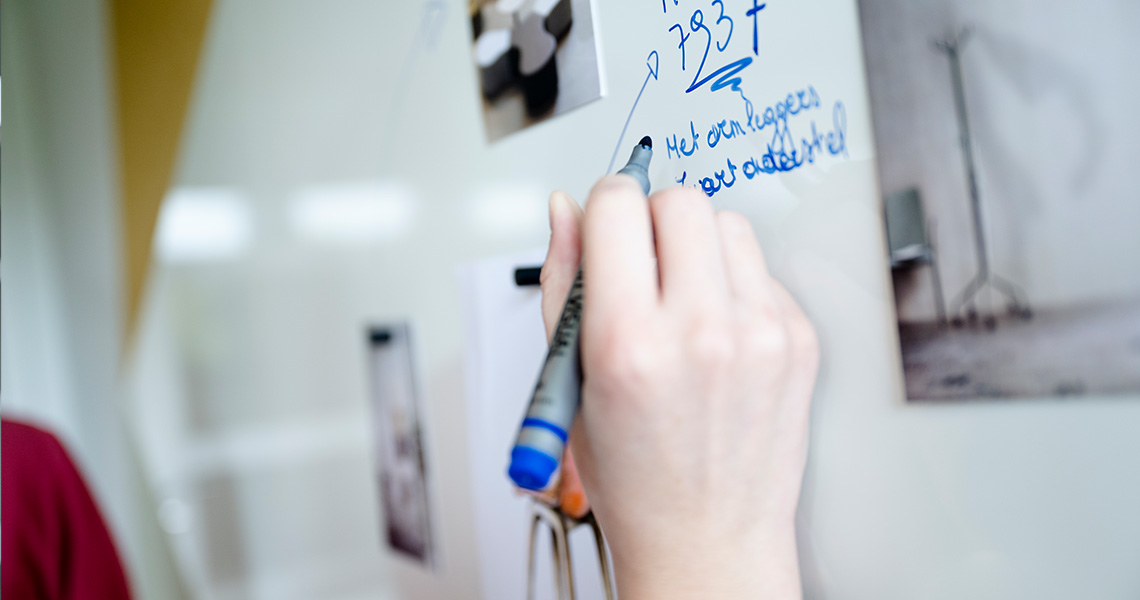 Close-up of a hand writing on a custom magnetic whiteboard