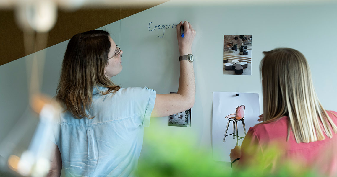 Colleague writing a heading on a custom whiteboard wall