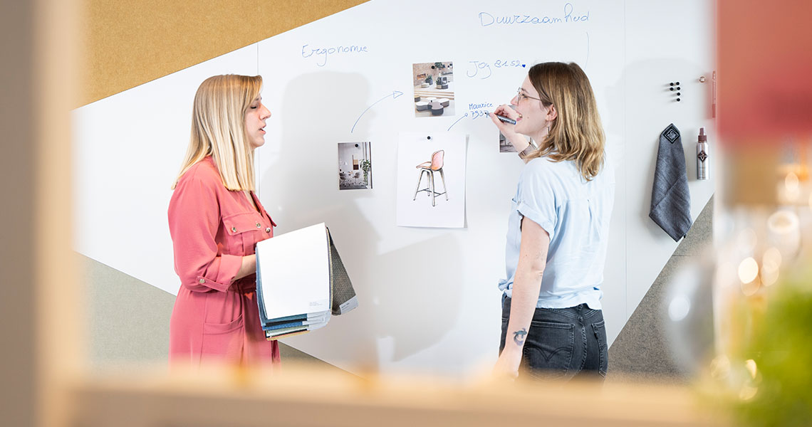 Two colleagues collaborating beside a custom whiteboard wall