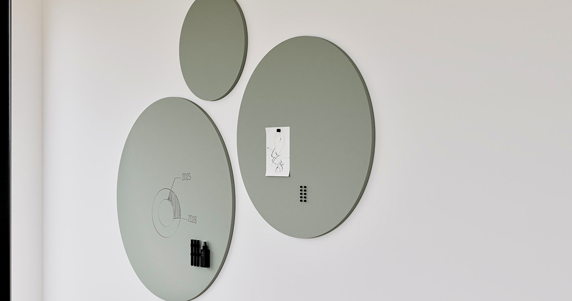 Round design whiteboards of varying sizes mounted on a plain office wall