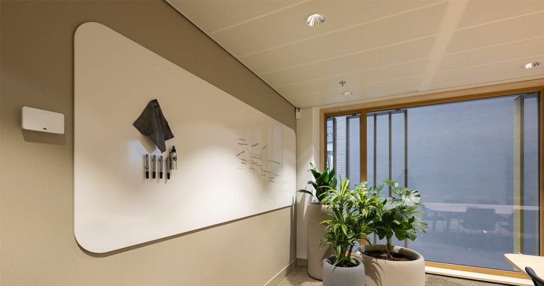 Overview of a frameless whiteboard panel installed in an office interior