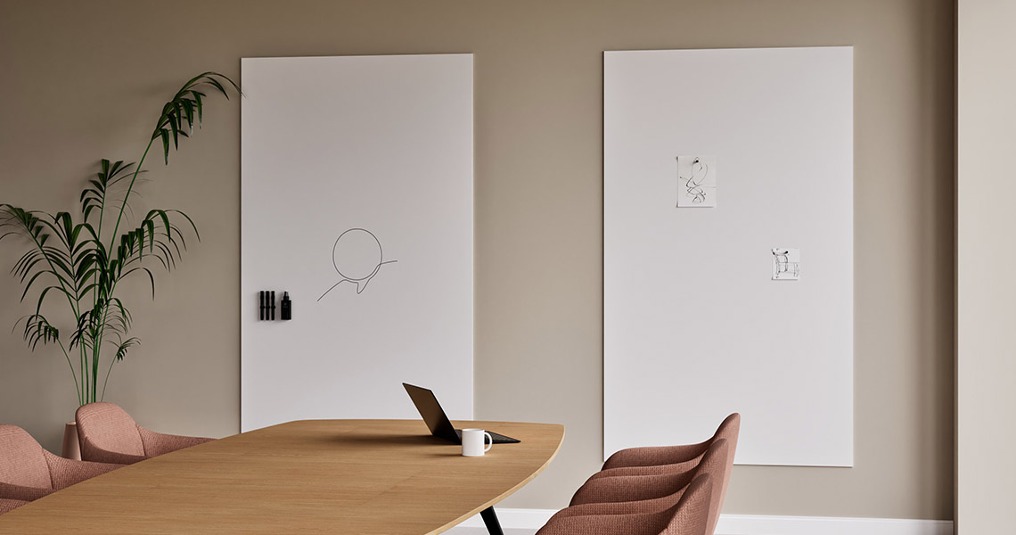 Team members writing on a large dry erase board during a planning session