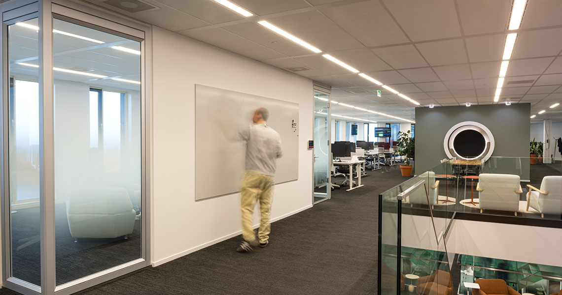 Whiteboard wall installed in a bright open-plan office with desks in the foreground