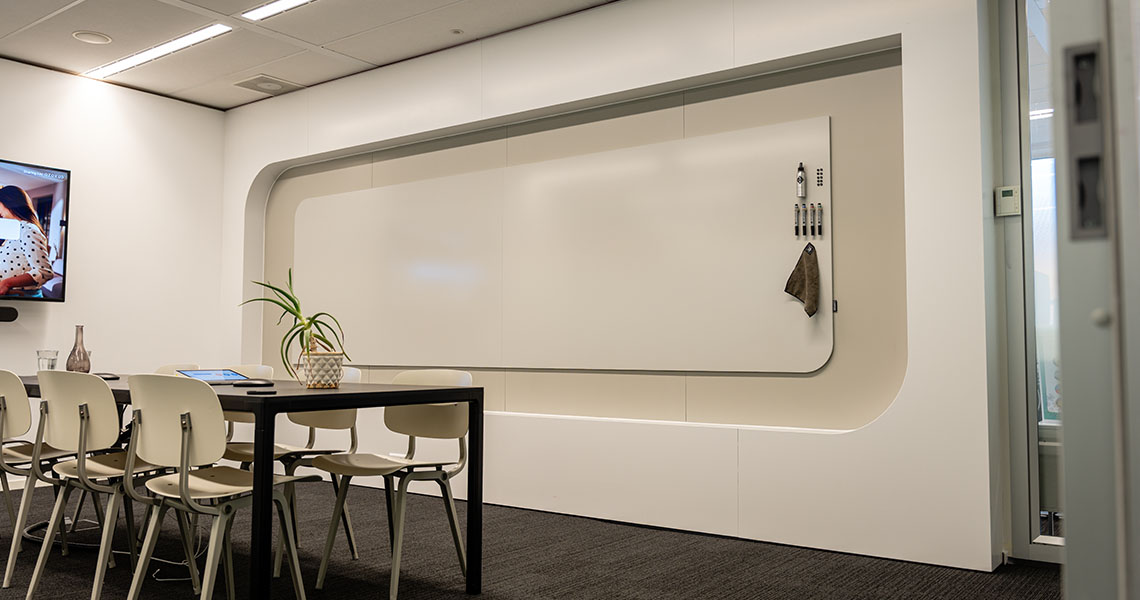 Rounded-corner whiteboard wall installed in a small meeting room with markers mounted alongside
