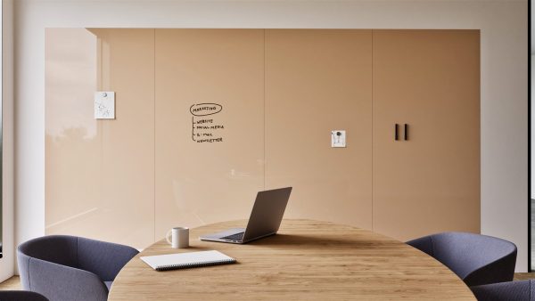 Glassboard wall panels: Sharp Glass Wall in beige, spanning four panels across a meeting room wall, with handwritten notes and magnetic memos attached, above a round table with a laptop and notebook.