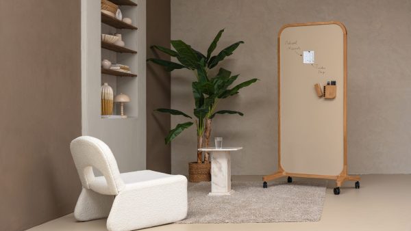 Mobile whiteboard on wheels next to a bookshelf with a plant